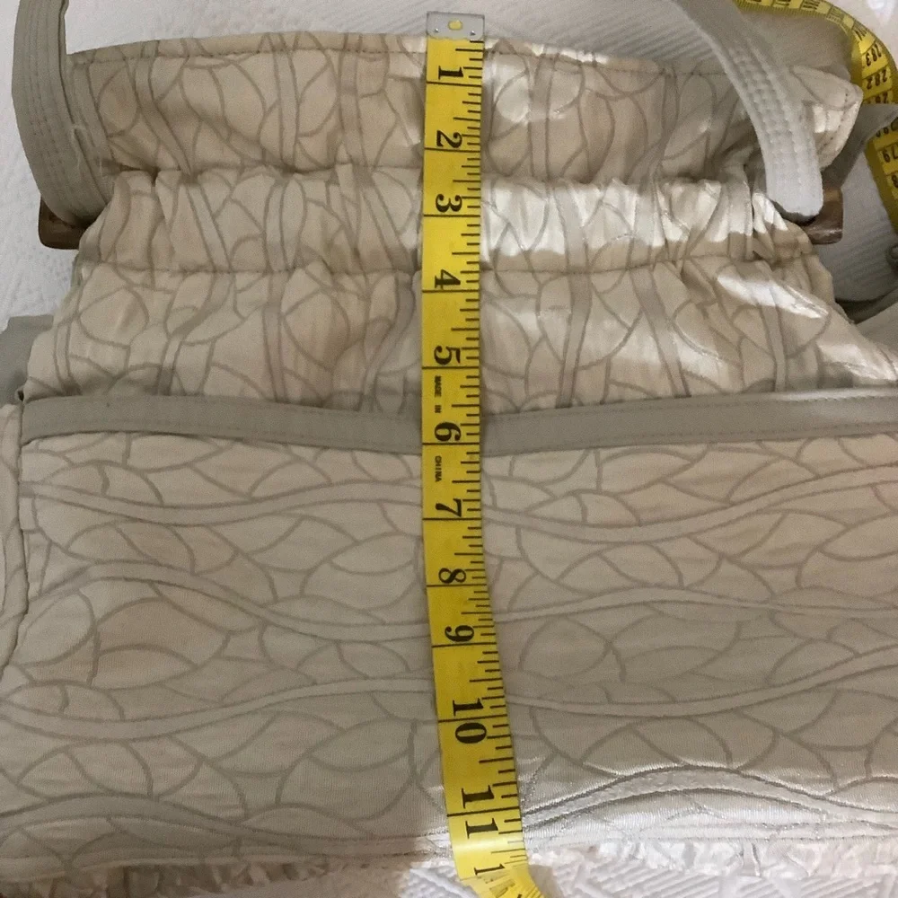 FABRIC SHOULDER BAG WITH OUTSIDE SURROUNDING POCKETS IN A CREAM AND TAUPE COLOR.